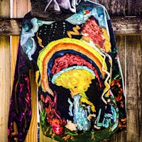 a colorful hoodie hanging on a fence
