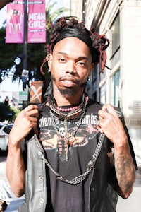 a man with dreadlocks standing on a city street